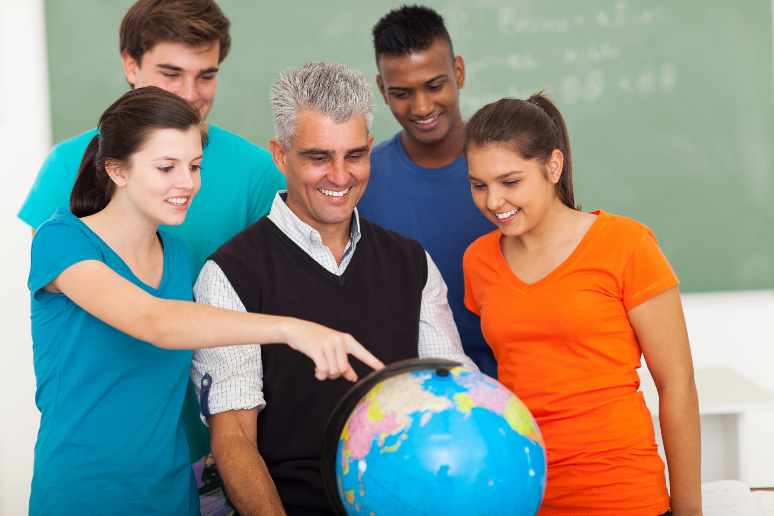 group of happy high school students and teacher looking at globe